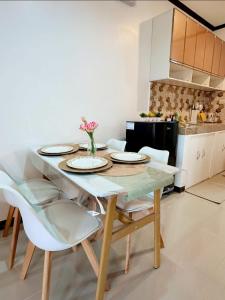 a dining room table with white chairs and a kitchen at A and A Homestay Tandag City  +21 photos
