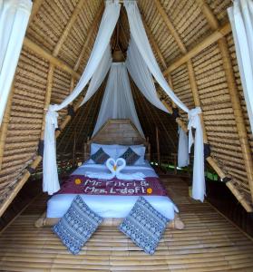 a bed in a thatched room with white curtains at Kumbuh Jungle in Susut