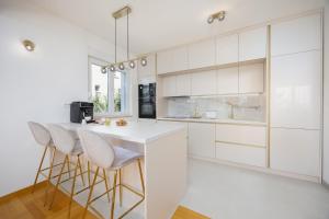een keuken met witte kasten en barkrukken bij Marivi - Luxury apartment above the beach Žnjan in Split +27 foto's
