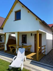 a white house with a deck and two chairs at DorJan - Domki Letniskowe in Dziwnówek +54 photos