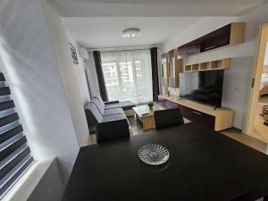 Una sala de estar con una mesa, un sofá y un televisor. en Cosy Place Milano, en Constanţa