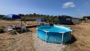 a swimming pool with a table and two umbrellas at Porto Experience Caravan in Santa Justa