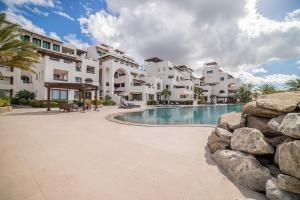a large building with a swimming pool next to a resort at Luxury Oceanfront Condo at El Caimancito Beach in La Paz