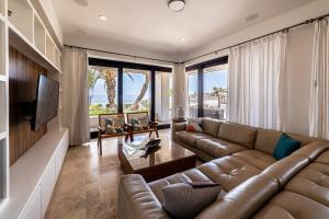 a living room with a leather couch and a television at Luxury Oceanfront Condo at El Caimancito Beach in La Paz