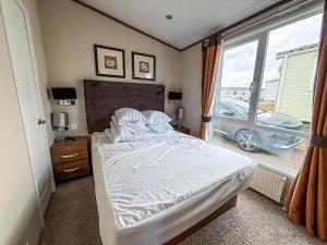 a bedroom with a bed and a window with a car outside at Stunning Caravan With Full Sea Views At Hopton Haven Ref 80044S in Great Yarmouth +16 photos