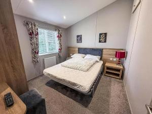 a small bedroom with a bed and a window at Stunning 4 Berth Lodge With Decking At Breydon Water In Norfolk Ref 10094B in Belton +22 photos