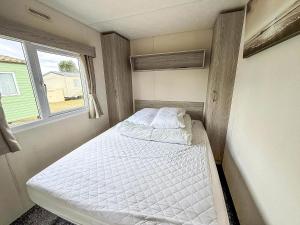 a small room with two beds in it with a window at Gorgeous Caravan With Decking In Breydon Water Holiday Park, Ref 10081B in Belton +10 photos