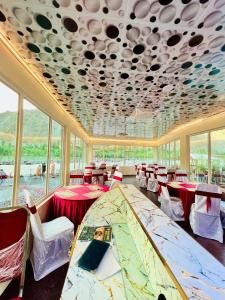 a dining room with tables and chairs and windows at Riverfront resort sooq valley in Dargai
