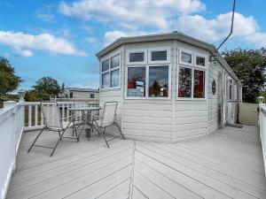 una casetta minuscola con tavolo e sedie su un ponte di Great Dog Friendly Caravan To Hire With Field Views In Norfolk Ref 10132B a Belton