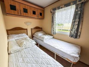 due letti in una piccola stanza con una finestra di Great Dog Friendly Caravan To Hire With Field Views In Norfolk Ref 10132B a Belton
