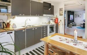 a kitchen with a wooden table and a counter top at Awesome Home In Östra Sönnarslöv in Östra Sönnarslöv