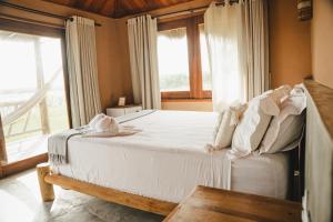a bedroom with a bed with white sheets and a window at Tatadise in Tatajuba