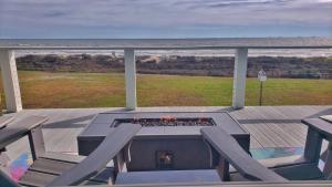 a deck with a table and chairs and a fire place at Beachfront - Hot Tub - Home Theater in Bolivar Peninsula