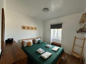 ein Schlafzimmer mit einem grünen Bett und Handtüchern darauf in der Unterkunft Green Sunrise House in Nordeste