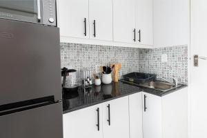 a kitchen with white cabinets and a black counter top at Die Kant - Hooggety in George