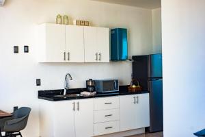 a kitchen with white cabinets and a black refrigerator at Mar Azul y Amanecer Desde la Cama in Mahahual