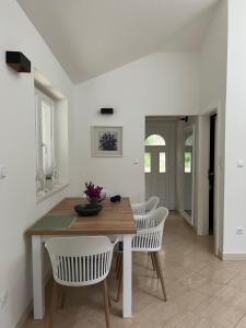 a dining room with a wooden table and white chairs at Korcula Apartment direkt am Meer -Zrnovska banja -2,5 km zur Altstadt Korcula in Korčula