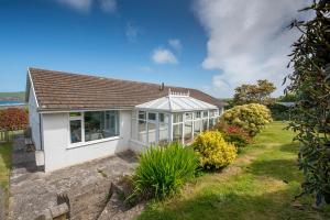 Una pequeña casa blanca con ventanas y plantas. en Awel Y Mor, en Newport