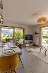 een eetkamer met een tafel, stoelen en een tv bij Tournette, vue montagne & belle terrasse in Annecy