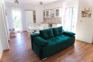 a living room with a green couch and a kitchen at APART HOTEL ASTERIA in Ljubljana