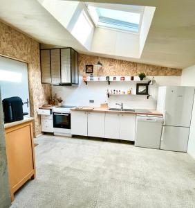 eine Küche mit weißen Geräten und einem Dachfenster in der Unterkunft Le Loft du Pré - Maison d'architecte - Le Mans in Le Mans