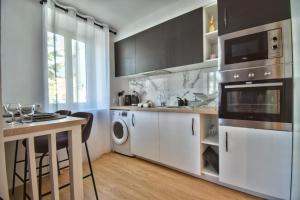 a kitchen with white cabinets and a sink and a dishwasher at Le Cocon de Maintenon in Maintenon +1 photo