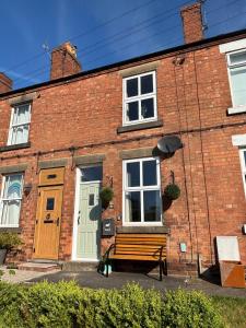 un bâtiment en briques avec un banc devant lui dans l'établissement Hill View Cottage, à Mappleton