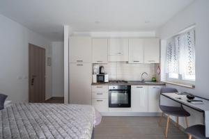 a kitchen with white cabinets and a bed in a room at Studio Istra in Rovinj