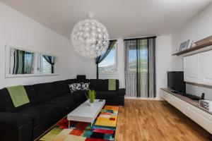 a living room with a black couch and a chandelier at Sky Split Apartment in Split