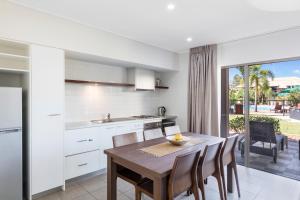 a kitchen and dining room with a table and chairs at Oaks Cable Beach Resort in Broome