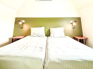 Un dormitorio con una cama con sábanas blancas y dos lámparas. en Holiday Home Beach House Westkapelle 103 D by Interhome, en Westkapelle