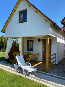 a house with a deck and a chair at DorJan - Domki Letniskowe in Dziwnówek