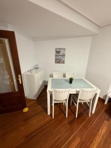 a dining room with a white table and chairs at El Rincón del Faro - Parking incluido in San Vicente de la Barquera
