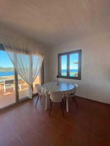 a dining room with a table and chairs and a balcony at Seagarden Home vista mare con giardino privato in Capo Coda Cavallo