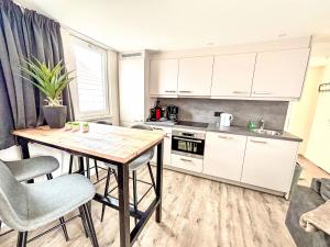 Una cocina con gabinetes blancos y una mesa de madera. en Holiday Home Beach House Westkapelle 2B by Interhome, en Westkapelle