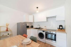 ロデーズにあるLEntre Deux : havre de paix entre nature villeの白いキャビネット、テーブル、洗濯機付きのキッチンが備わります。 +13枚の写真