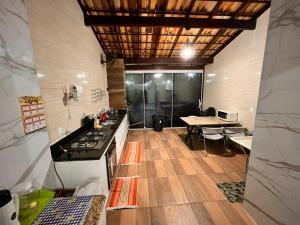 a kitchen with a stove and a table in it at Jacara Beach House - Seu Refúgio in Serra