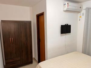 a bedroom with a bed and a cabinet and a air conditioner at Jacara Beach House - Seu Refúgio in Serra