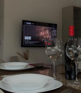 a table with two wine glasses and a tv on the wall at Azul Apartment Orikum in Orikum +19 photos