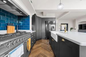 a kitchen with a stove and blue tiles at City SuperHost Hale Family Home in Hale +26 photos