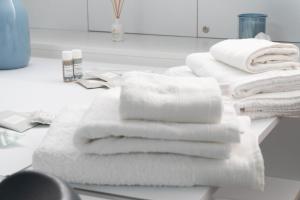 une pile de serviettes blanches assises sur un comptoir de salle de bains dans l'établissement Elementi B&B, à Altamura 29 autres photos