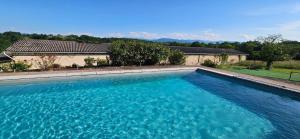 a large blue swimming pool in front of a house at Le gîte du besson in Cassagne