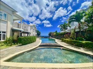 a swimming pool in the middle of a house at Sea view Ginger apartment in Pointe aux Biches