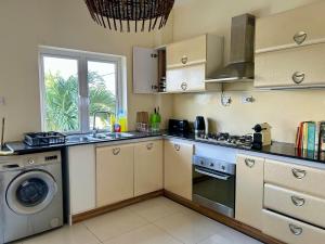 a kitchen with a stove and a sink and a washing machine at Sea view Ginger apartment in Pointe aux Biches