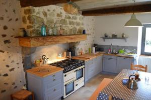 a kitchen with a stove and a table in it at Gite Les Arrebourits 4 étoiles in Anères