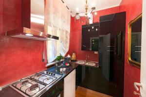 cocina con paredes rojas, fogones y fregadero en Verona Centre Apartments, en Verona