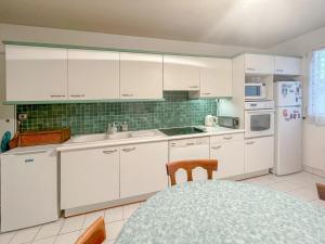 Una cocina con gabinetes blancos y un refrigerador blanco. en La Clé de Marc, en Le Vésinet