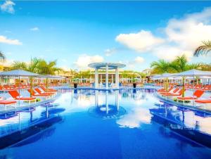a resort pool with red chairs and umbrellas at Moon Palace The Grand Cancun All Inclusive in Cancún