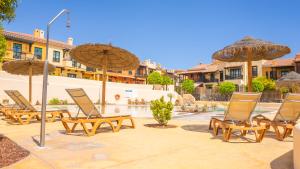 a group of chairs and umbrellas on a patio at Villa Luisa - Relax with Ocean View and Pool in San Miguel de Abona