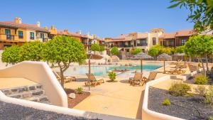 a swimming pool with chairs and trees and buildings at Villa Luisa - Relax with Ocean View and Pool in San Miguel de Abona